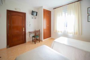 a bedroom with a bed and a table and a window at Los Gallos in Casabermeja