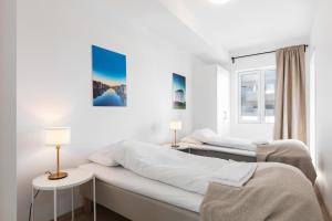 two beds in a white room with two lamps at Forenom Serviced Apartments Trondheim in Trondheim