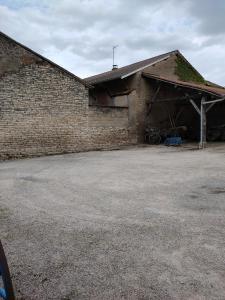 un edificio de ladrillo con un estacionamiento delante de él en La ferme du Grand Faubourg, en Pont-de-Vaux