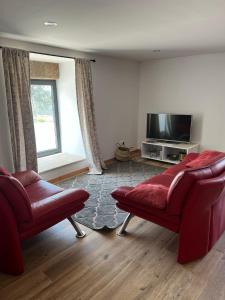 a living room with two red chairs and a flat screen tv at Casa do Borges 