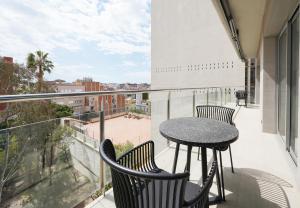 numa I Colmena Apartments في برشلونة: بلكونه مع طاوله وكراسي واطلاله