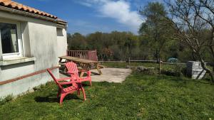 duas cadeiras vermelhas e uma mesa de piquenique num quintal em Gite la Péraie - Le Roseau em Treize-Vents
