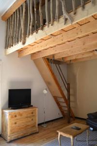 le p'tit studio au calme au pied du Jura : غرفة معيشة مع تلفزيون على خزانة خشبية ودرج
