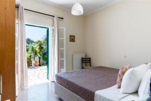 a bedroom with a bed and a sliding glass door at Ipsos & Barbati Panoramic Views by Konnect in Ipsos