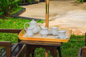 a wooden table with four tea sets on it at Tranquill Villa La Dimora in Gampaha