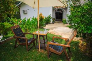 2 sillas y una mesa con sombrilla en un patio en Tranquill Villa La Dimora, en Gampaha