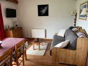 uma sala de estar com um sofá e uma mesa em Appartement LA MARMOTTE DU DEVOLUY em Le Dévoluy