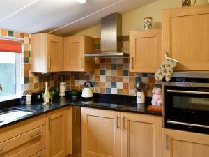 a kitchen with wooden cabinets and black counter tops at Shirleys Cottage in Othery