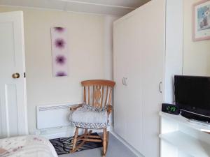 a room with a wooden chair and a television at Shirleys Cottage in Othery