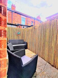 a fence with two chairs in front of a wooden fence at Cosy & Stylish 2 Bedroom House, King-bed & more in Hull