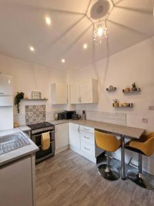 a kitchen with white cabinets and a table and chairs at Cosy & Stylish 2 Bedroom House, King-bed & more in Hull