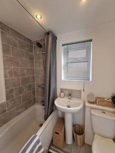 a bathroom with a sink and a toilet and a tub at Cosy & Stylish 2 Bedroom House, King-bed & more in Hull