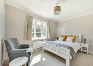 a white bedroom with a bed and a chair at 1 Lux Farm Cottages in Playford