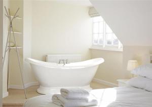 a white bathroom with a tub and a bed at 10 The Whinlands in Thorpeness