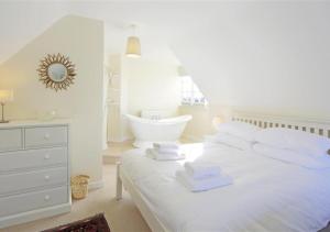 a white bedroom with a white bed and a bath tub at 10 The Whinlands in Thorpeness