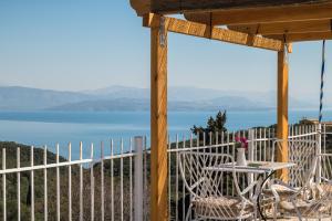 a table and chairs on a porch with a view of the water at Ipsos & Barbati Panoramic Views by Konnect in Ipsos