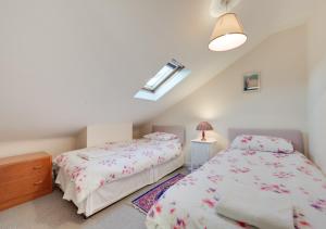 a bedroom with two beds and a dresser and a window at 1 The Knoll in Shottisham