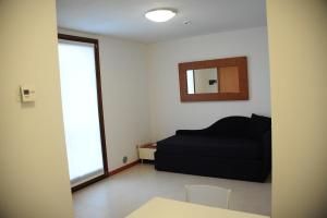ein Wohnzimmer mit einem schwarzen Sofa und einem Spiegel in der Unterkunft Suite Maria in Buttrio