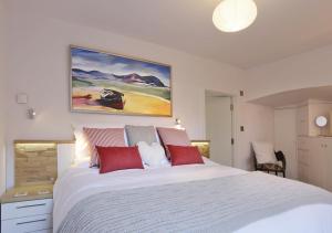 ein Schlafzimmer mit einem großen weißen Bett mit roten Kissen in der Unterkunft 1 White Point in Southwold