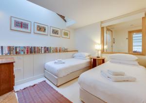 a bedroom with two beds and a book shelf at 2 The Courtyard in Snape