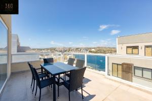 einen Tisch und Stühle auf einem Balkon mit Meerblick in der Unterkunft Luxurious Sea front Penthouse with private HOT TUB by 360 Estates in St Paul's Bay