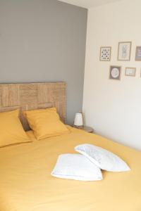 a yellow bed with two pillows on top of it at Les Gîtes du Vallon du Trunvel in Plonéour-Lanvern