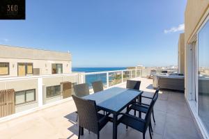 einen Tisch und Stühle auf einem Balkon mit Meerblick in der Unterkunft Luxurious Sea front Penthouse with private HOT TUB by 360 Estates in St Paul's Bay