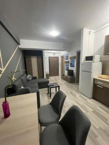 ein Wohnzimmer mit einem Sofa und Stühlen sowie eine Küche in der Unterkunft Kiraz Apartament Summerland in Mamaia