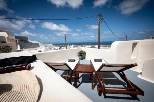a balcony with chairs and a table on the roof at Lotza Studios in Oia