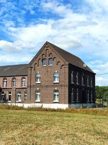 um grande edifício de tijolos com um campo em frente em Michelshof em Kevelaer