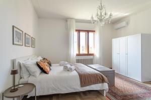 a white bedroom with a bed and a chandelier at Casa Cairoli in Mira