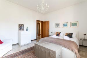 a white bedroom with a large bed and a chandelier at Casa Cairoli in Mira