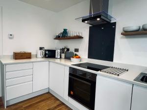 a kitchen with white cabinets and a black stove top oven at Spinney on the Green in Woodhall Spa