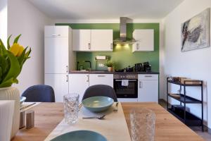 une cuisine avec des placards blancs et une table en bois dans l'établissement nice2be Apartments, à Augsbourg
