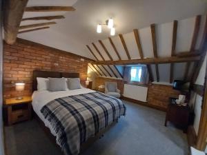 1 dormitorio con cama y pared de ladrillo en The Dolfor Inn en Newtown