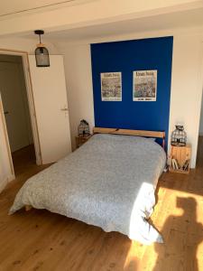 a bedroom with a large bed with a blue wall at Authentique maison de pêcheur à Port-en-Bessin in Port-en-Bessin-Huppain