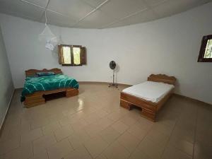 a bedroom with two beds and a fan in it at Complete House in the jungle, near the sea. in Kafountine