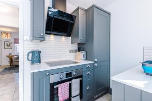 uma cozinha com armários azuis e uma televisão por cima de um fogão em Stylish Home with Canal Views em Chester