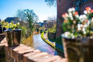 a brick fence with flowers on it next to a river at Stylish Home with Canal Views in Chester