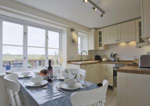 een keuken met een tafel met witte stoelen en een eetkamer bij 4 Blackshore in Southwold