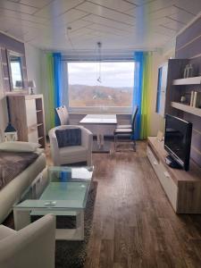 ein Wohnzimmer mit einem Sofa, einem Tisch und einem TV in der Unterkunft Plön - Traumhafter Seeblick in Plön