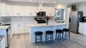 una cucina con armadi bianchi e un'isola blu con sgabelli da bar di Brand New 2 Bedroom Cottage on Seneca Lake a Himrod