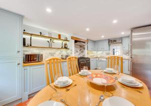 una cocina con una mesa de madera con platos y vasos. en 5 River Lane, en Halesworth