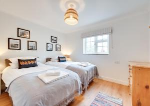 two beds in a room with white walls and a window at 5 The Martins in Walberswick