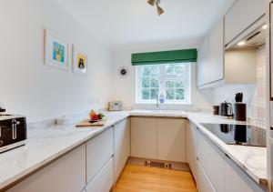 a kitchen with white cabinets and a window at 5 The Martins in Walberswick