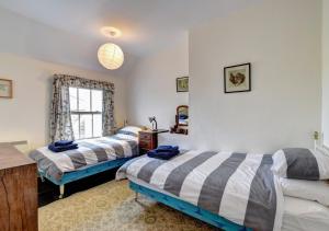 a bedroom with two beds and a window at 6 Coastguard Cottages in Hollesley