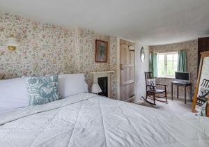 a bedroom with a large white bed and floral wallpaper at 9 Gate Cottage in Long Melford