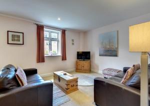 ein Wohnzimmer mit 2 Ledersofas und einem TV in der Unterkunft Amrose Cottage in Blythburgh