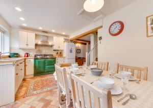 een keuken met een tafel met stoelen en een klok aan de muur bij Anchor Cottage in Woodbridge