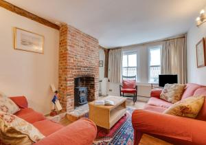 a living room with a brick fireplace and red couches at Anchor Cottage in Woodbridge